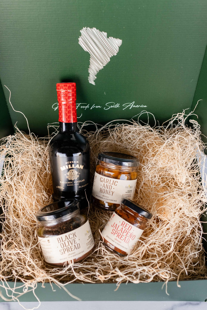Gift box featuring a selection of gourmet items: Millan Aged Balsamic Vinegar, Black Olive Spread, Garlic and Honey, Red Jalapeño Spread, and a Custom Full Olive Gift Box, perfect for culinary enthusiasts