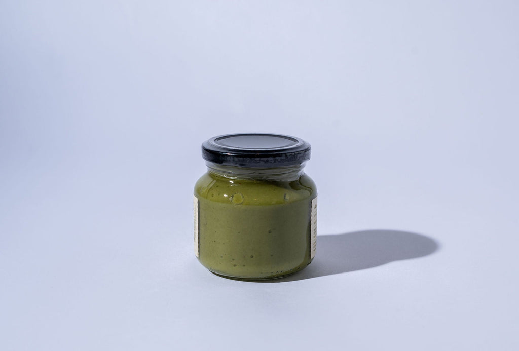 big jar of green olive spread on a white background