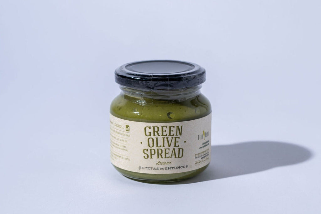 Jar of green olive spread on a light gray background