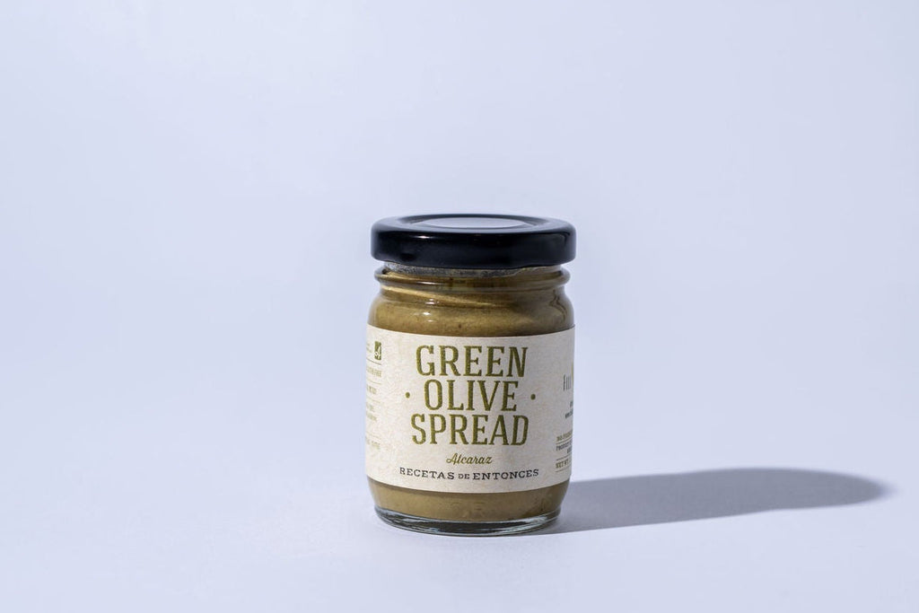 Jar of green olive spread on a light gray background
