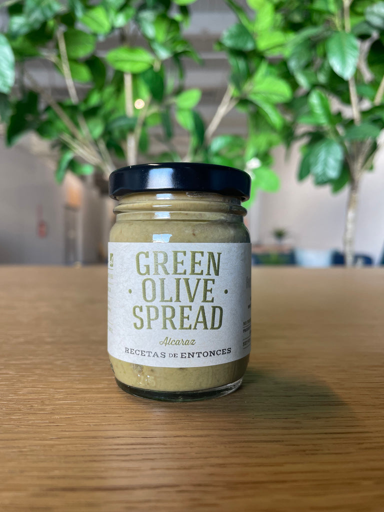 A small jar of Green Olive Spread, featuring a label that highlights the rich green color and savory nature of the spread