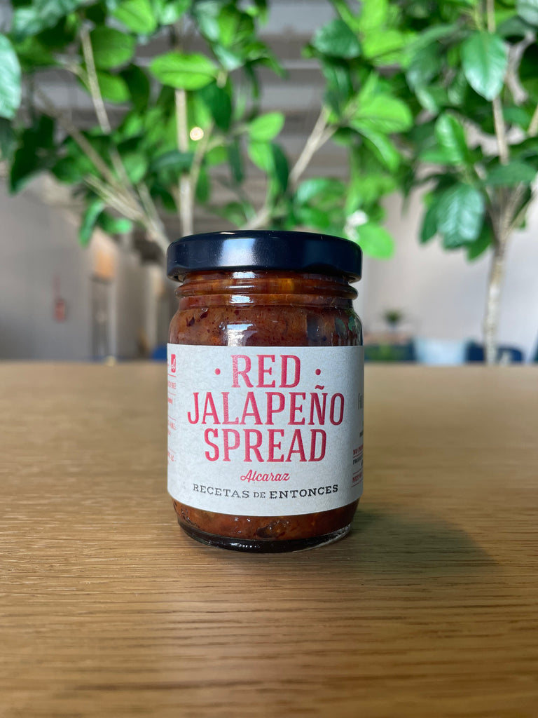 A small bottle of Red Jalapeño Spread, with a vibrant red label showcasing the spicy and flavorful nature of the product