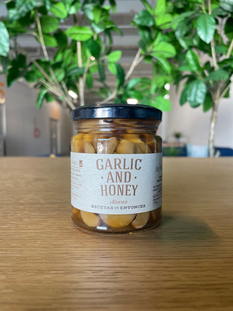A jar of whole garlic cloves combined with honey, showcasing the natural textures of the garlic and the golden color of the honey