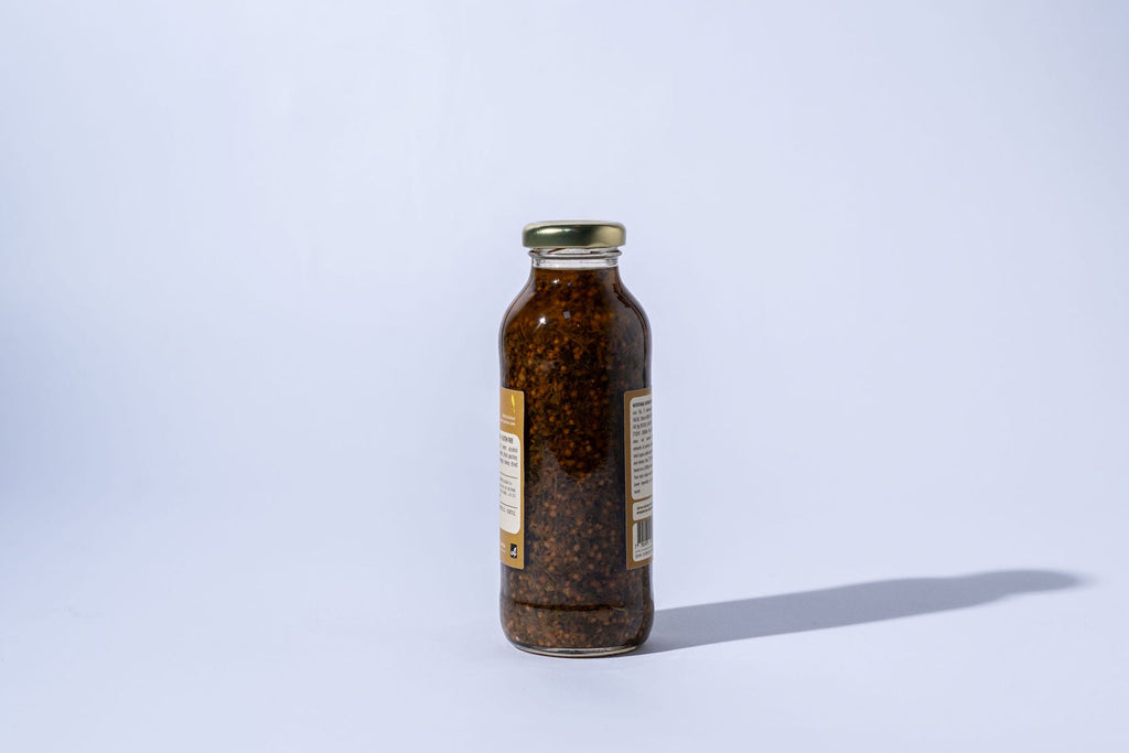 Small glass bottle of chimichurri with a label on a white background