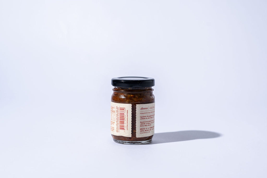 Small jar with a label on a white background with jalapenos