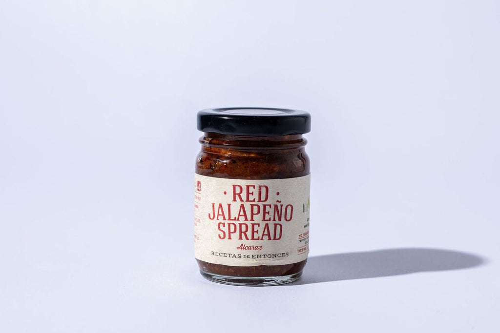 Jar of red jalapeno spread on a white background