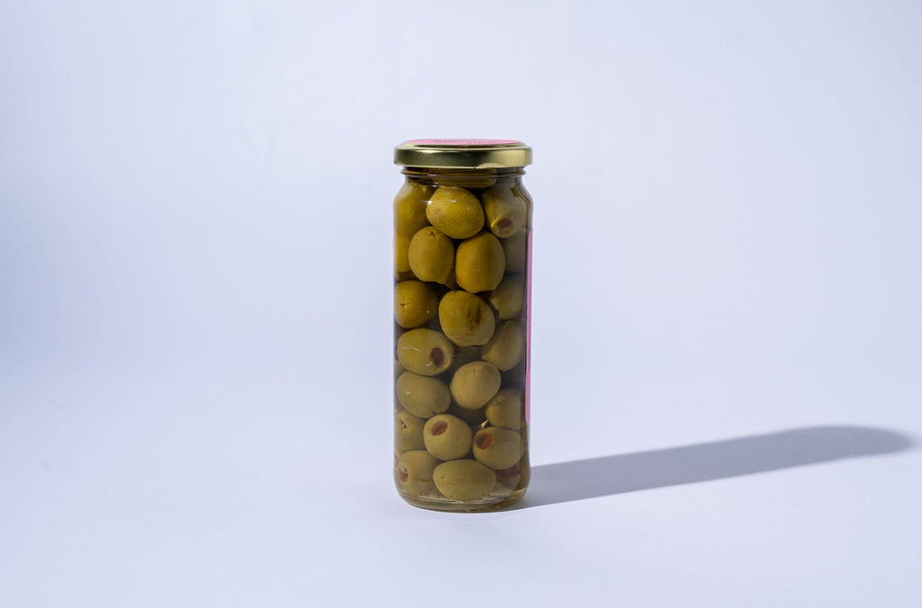 Jar of green olives on a white background with pink label