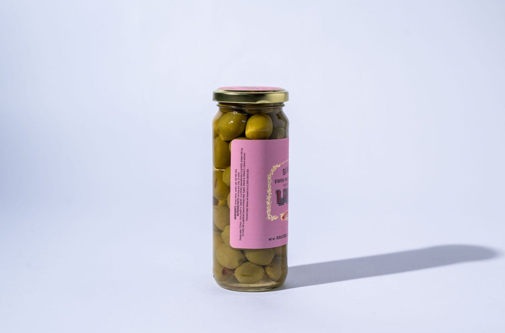 Jar of green olives with a pink label on a white background