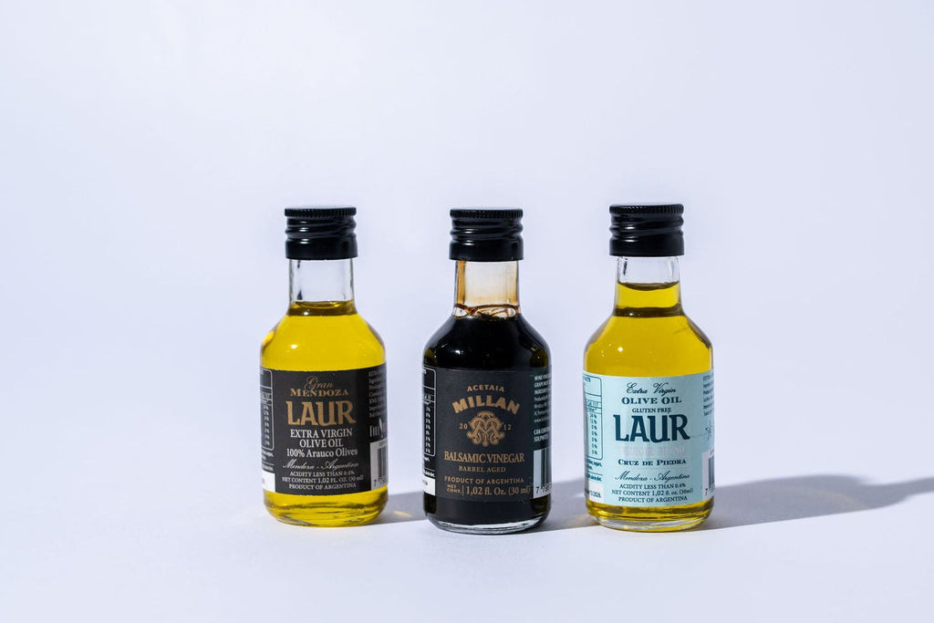 Three miniature bottles of olive oil  and vinegar on a white background