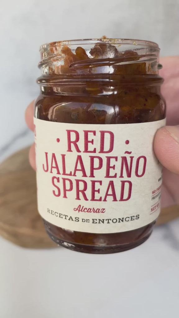 A video showing Red Jalapeño Spread being smoothly spread onto a cracker, highlighting the deep red color and texture of the spread