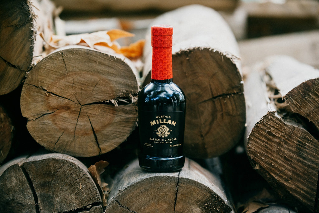 Bottle of Millan Aged Balsamic Vinegar on a log background